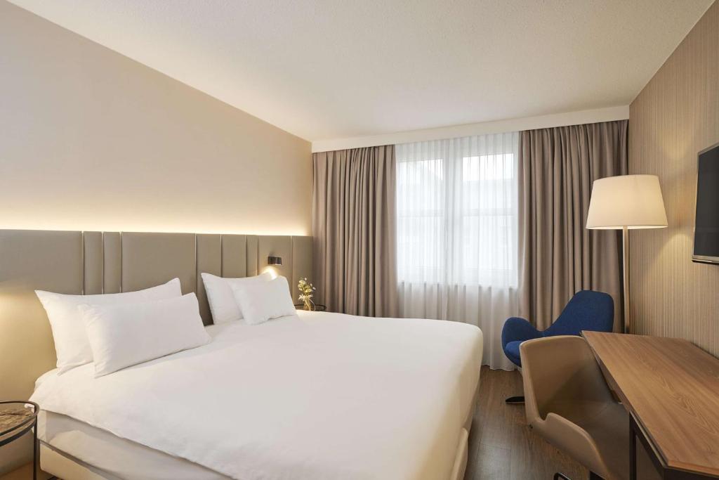 
a hotel room with a large bed and a large window at NH Frankfurt Airport in Kelsterbach
