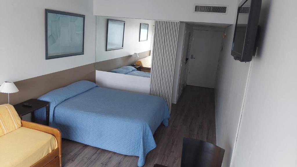 Dormitorio pequeño con cama azul y TV en edificio corrientes818 en Buenos Aires
