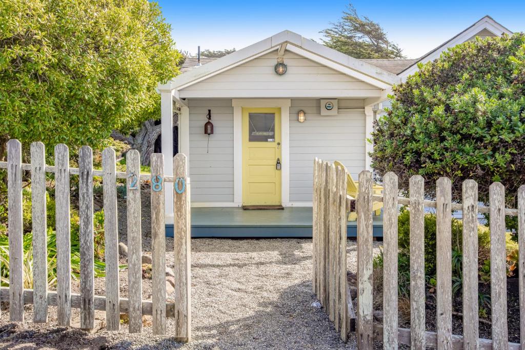 a wooden fence in front of a house with a yellow door at Seaside Cottage in Bodega Bay