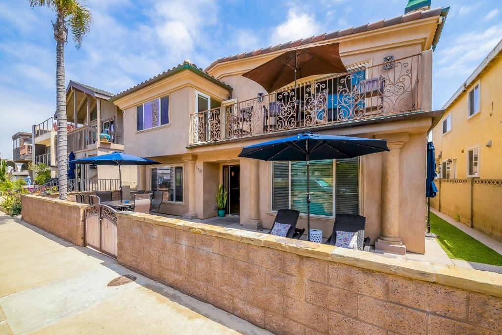 a house with a balcony with chairs and an umbrella at Palm Tree Getaway in Newport Beach