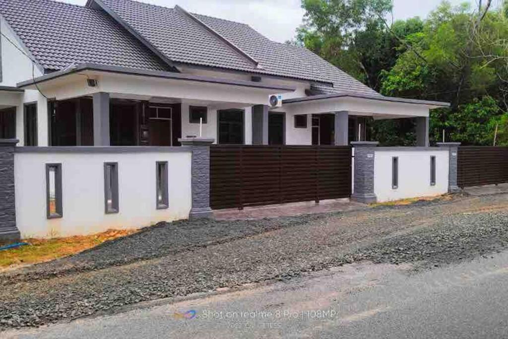 a white house with a fence on a street at afza Homestay Paka B in Paka