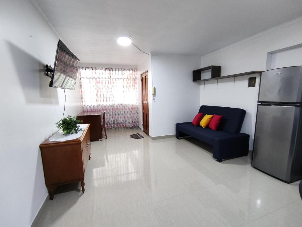 - un salon avec un canapé bleu et un réfrigérateur dans l'établissement MINI DEPARTAMENTO LAS VEGAS, à Chimbote