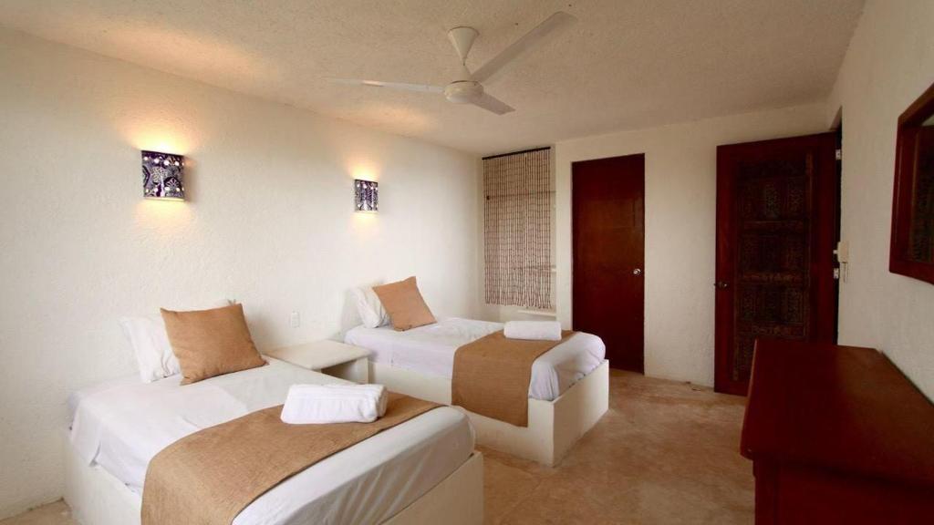 a hotel room with two beds and a couch at Casa Amor Pto Morelos in Puerto Morelos