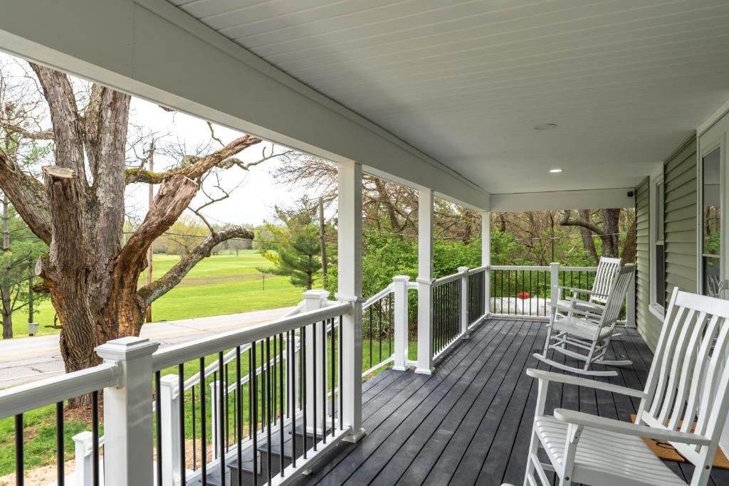 a porch with white rocking chairs and a tree at SAND HILL COTTAGE 3 Bedroom Home near PURDUE! River & Park View in West Lafayette