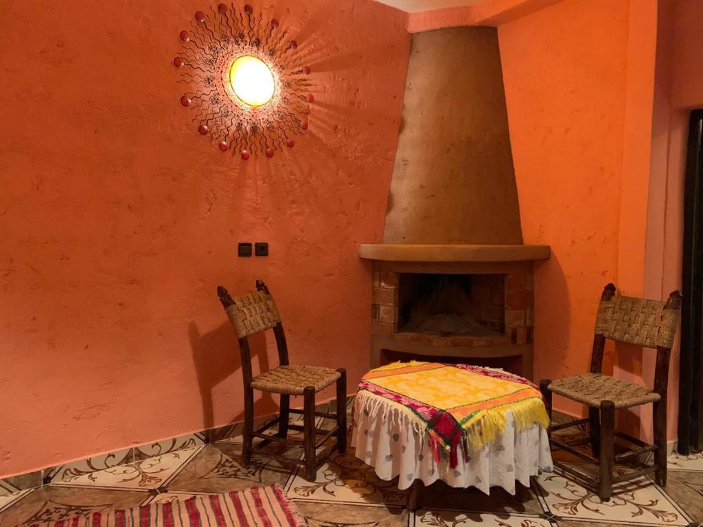 Habitación con chimenea, 2 sillas y mesa. en Auberge Le Mouflon en Ouirgane