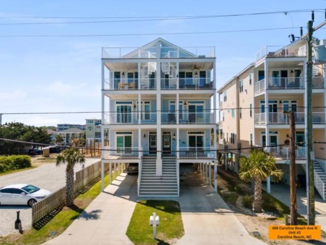 a large white building with a staircase in front of it at Pelican Watch - Steps away from a beautiful beach in a prime location home in Carolina Beach