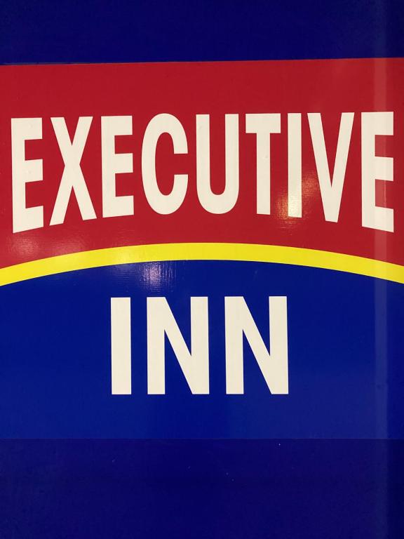 um sinal vermelho amarelo e azul com a estalagem exclusiva em Executive Inn em McPherson
