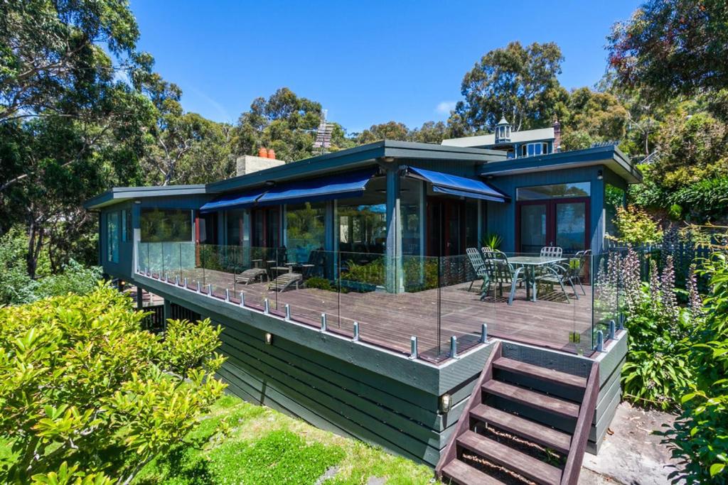 a green house with a deck with a table at The Grove in Lorne