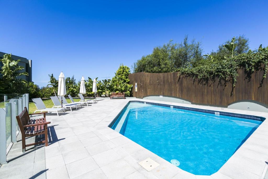 a swimming pool with chairs and a fence at Lorne Chalet Apartment 38 in Lorne