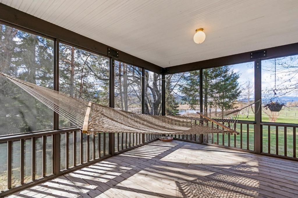 a hammock on a screened in porch with windows at The Wild Rose in Sagle