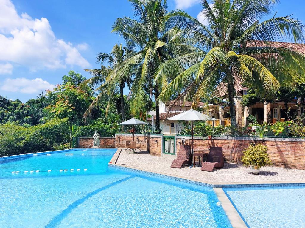 a swimming pool with two chairs and a house at Hotel Deli River and Restaurant Omlandia in Medan