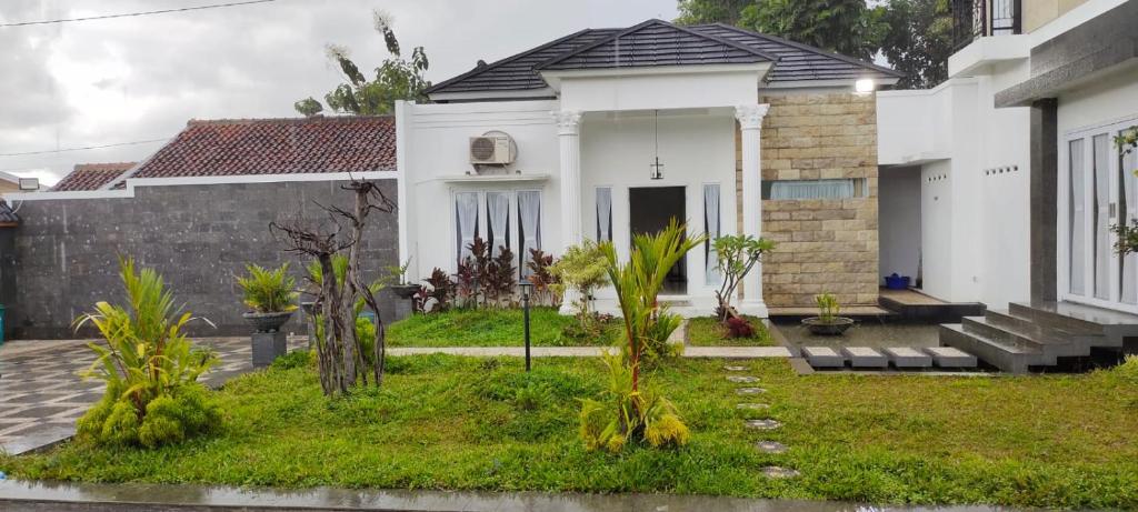 a white house with a yard with palm trees at Villa Azalea in Cireungit