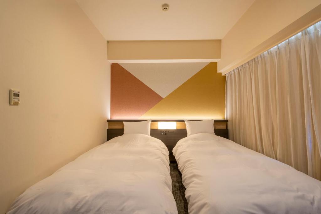 two beds in a small room with a window at Hotel Kanazawa in Kanazawa