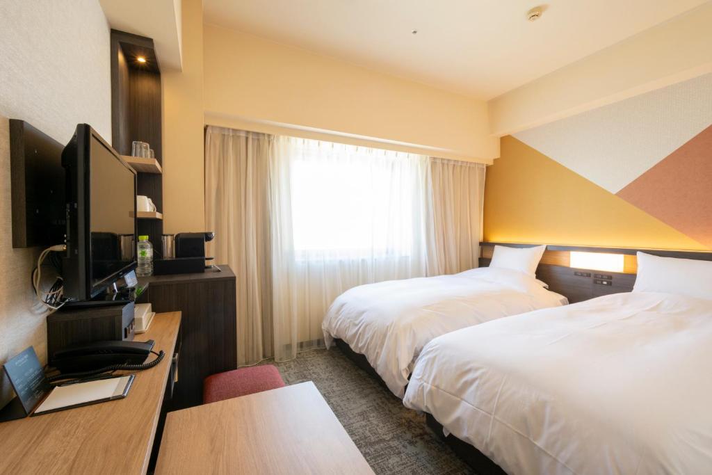 a hotel room with two beds and a television at Hotel Kanazawa in Kanazawa