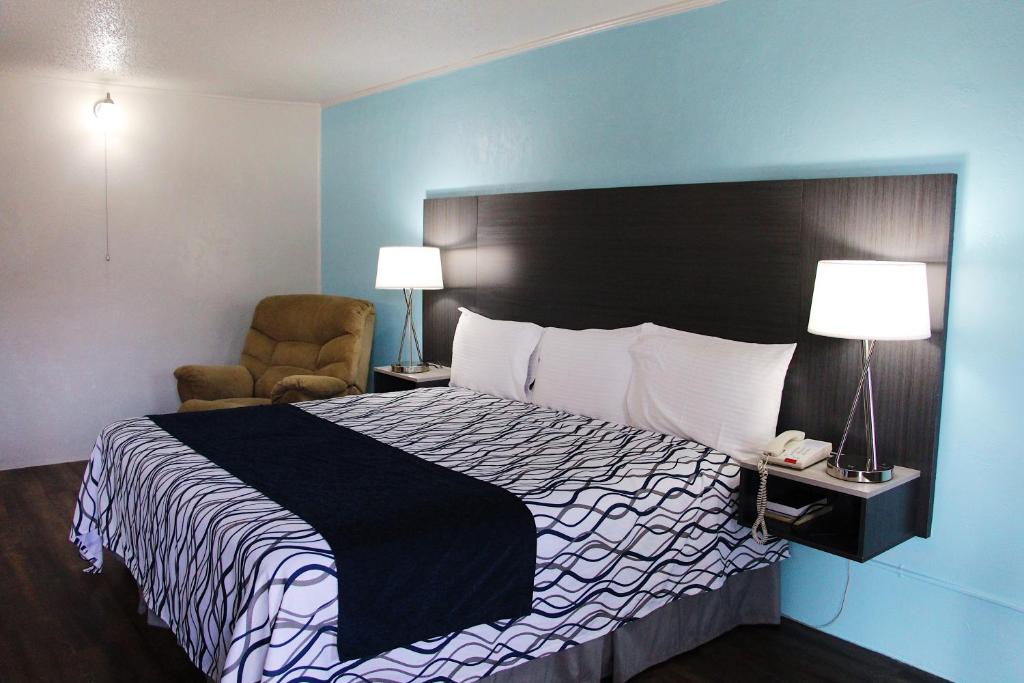 a hotel room with a bed and a chair at TexInn Motel New Boston in New Boston