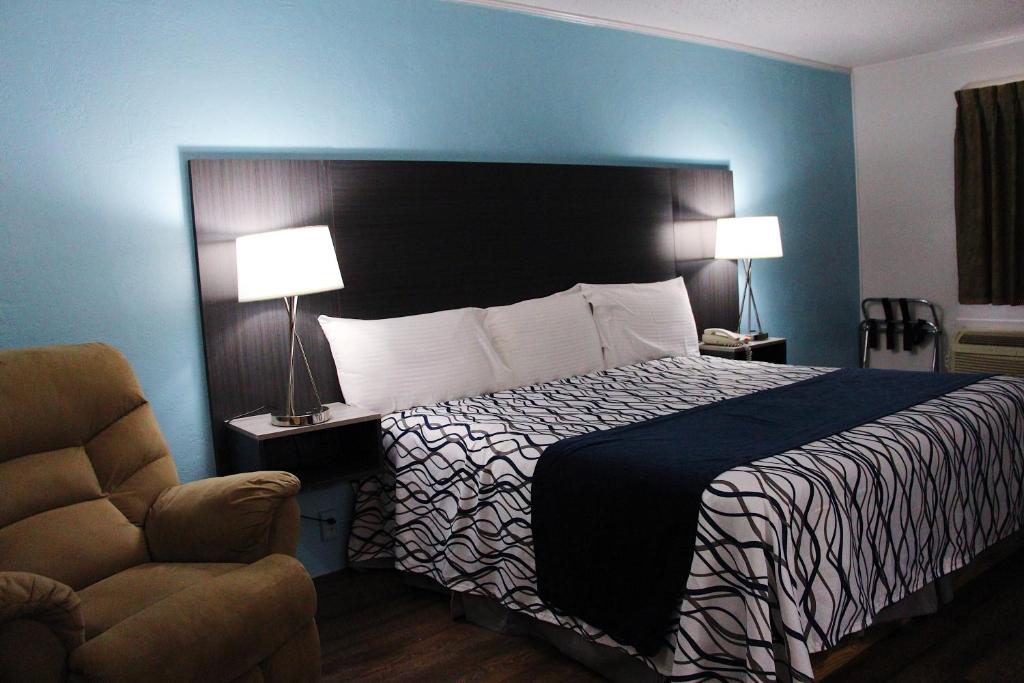 a hotel room with a bed and a chair at TexInn Motel New Boston in New Boston