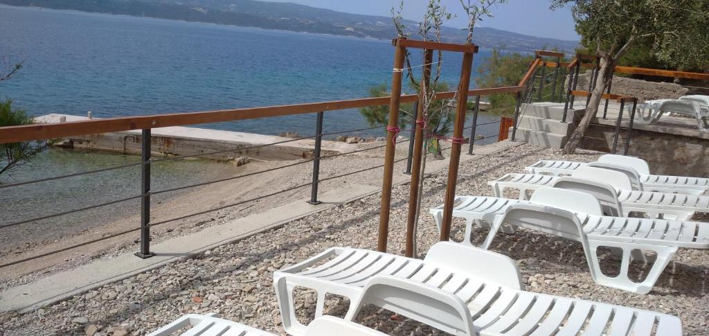 a row of white chairs sitting next to the water at Apartments Vucak in Stanići