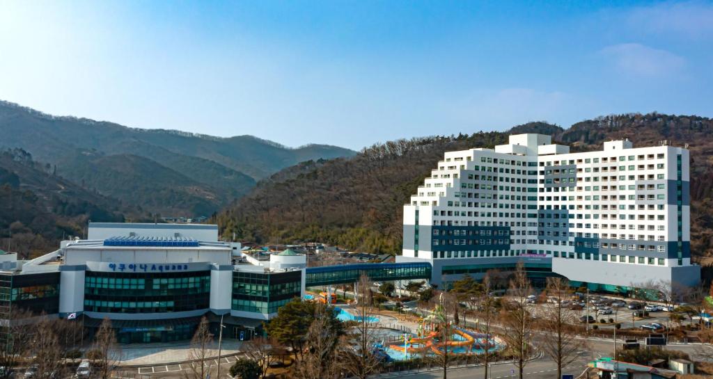 Kumho Hwasun Spa Resort في Hwasun: مبنى ابيض كبير امام جبل