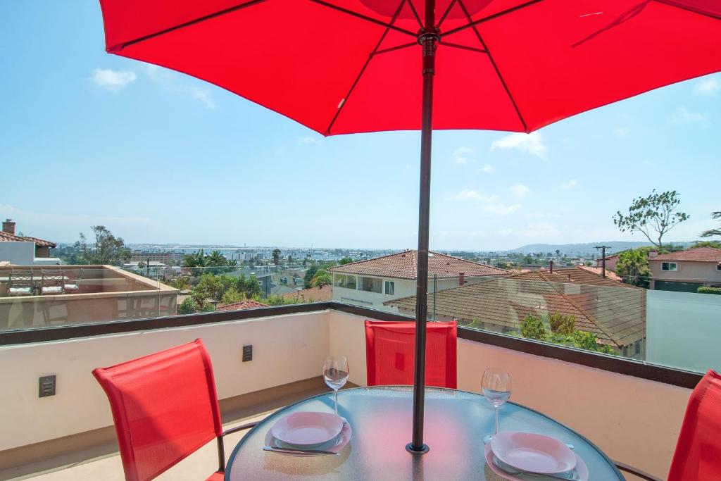 - une table avec un parasol rouge sur le balcon dans l'établissement Plum Summer Unit B, à San Diego