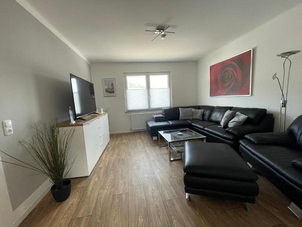 a living room with a black couch and a tv at Gästehaus Trulla in Bremm