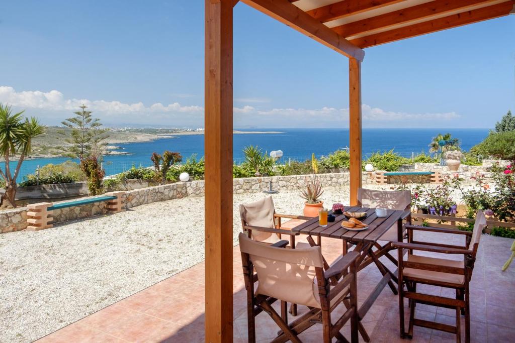 einen Tisch und Stühle auf einer Terrasse mit Meerblick in der Unterkunft Seashore Apartments in Chorafakia