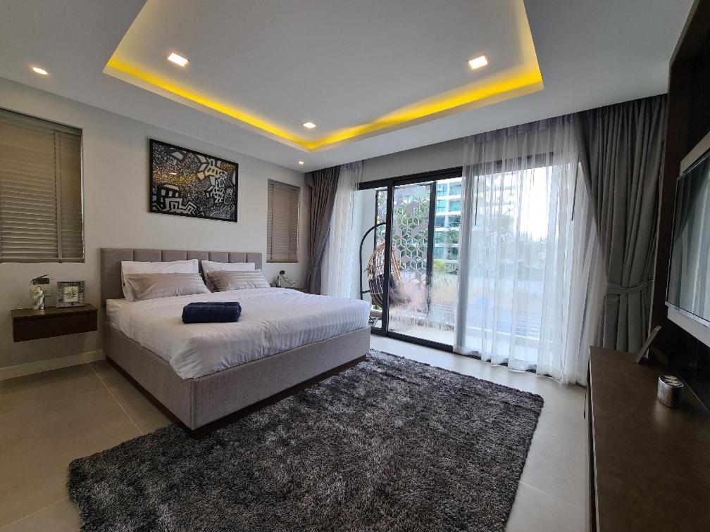 a bedroom with a large bed and a large window at Serenity Jomtien Pool Villas in Jomtien Beach