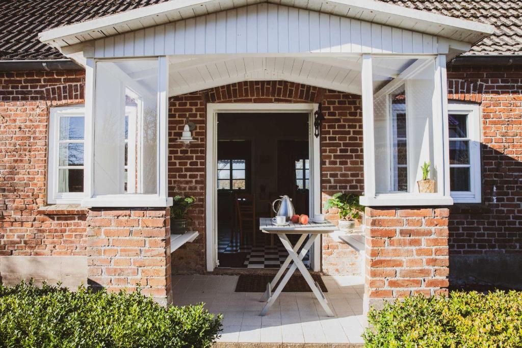 a brick house with an awning and a table at Ferienhaus Lüttes Landhuus in Oersberg