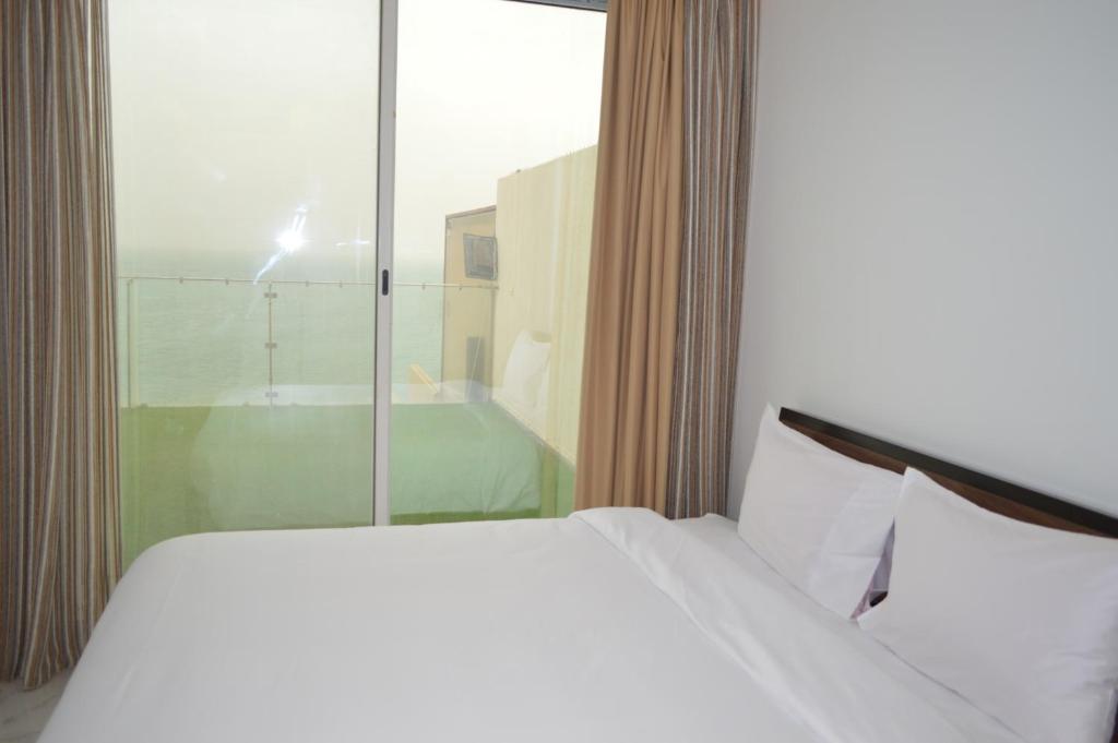 a bedroom with a white bed and a window and a tub at شاليهات ويف -Wave Resort in Al Khobar