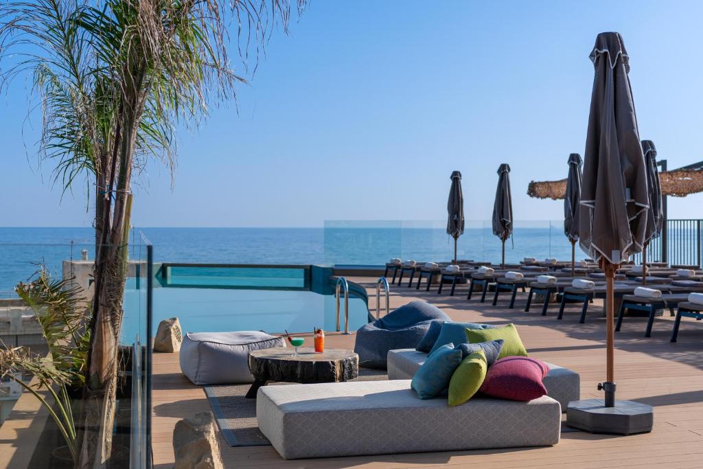 a patio with a couch and tables and an umbrella at Minos Ambassador Suites & Spa - Adults only in Rethymno Town