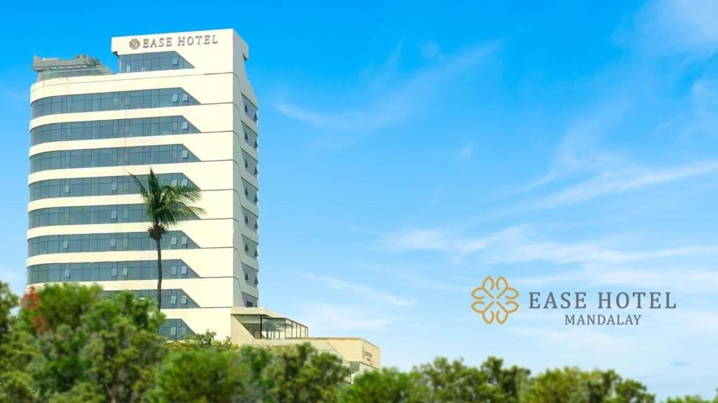 ein Hotel mit einer Palme vor einem Gebäude in der Unterkunft Ease Hotel in Mandalay