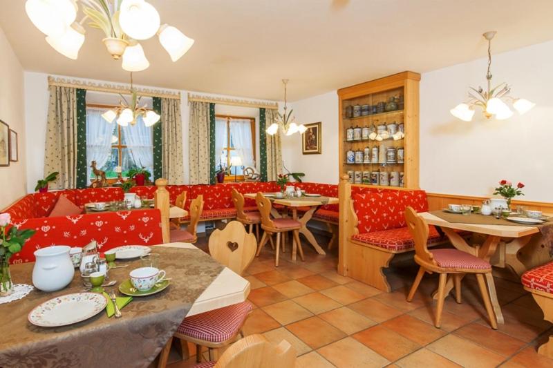 ein Restaurant mit Tischen, roten Stühlen und einem Tischler in der Unterkunft Gästehaus beim Foidlmoar Familie Höflinger in Reit im Winkl