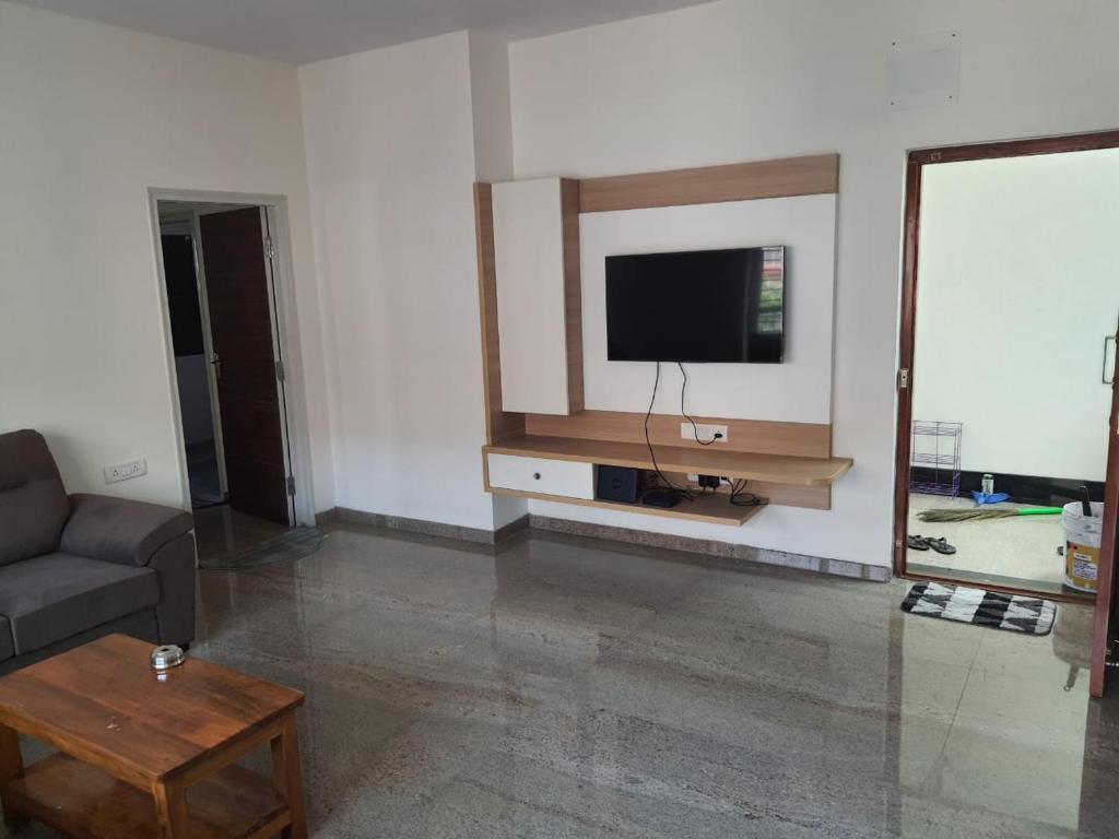 uma sala de estar com um sofá e uma televisão na parede em Castle BGR em Bangalore