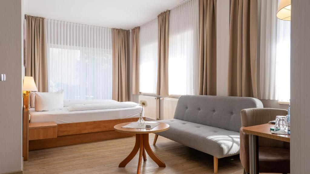 a hotel room with a bed and a couch at Hotel Am Uenglinger Tor in Stendal