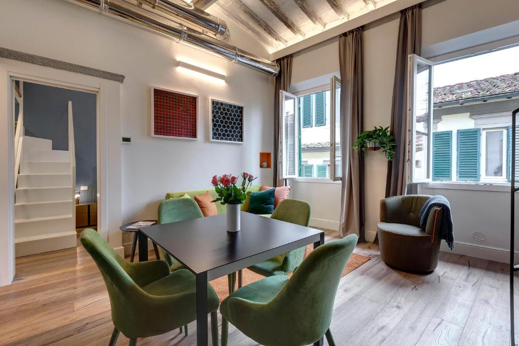 a living room with a table and green chairs at Turandot Apartment by Mamo Florence in Florence