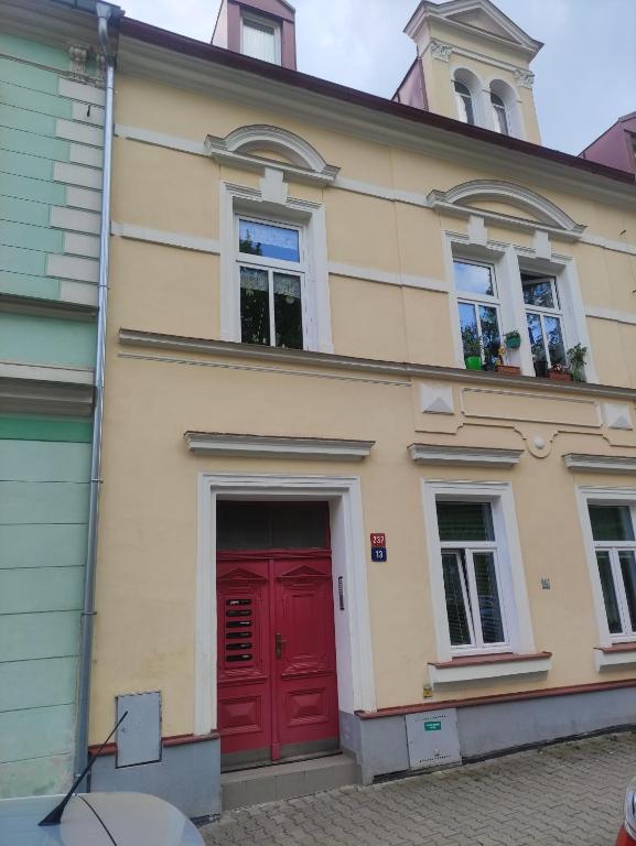 una casa con una puerta roja y dos ventanas en Apartmán Jena en Mariánské Lázně