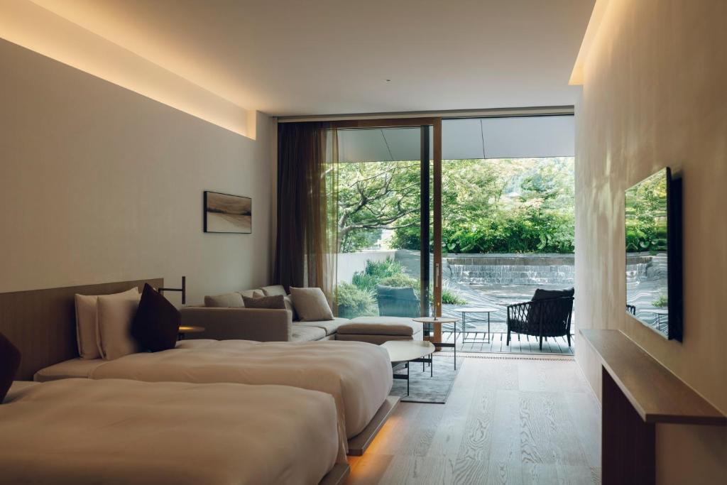 a hotel room with two beds and a living room at MUNI KYOTO by Onko Chishin in Kyoto