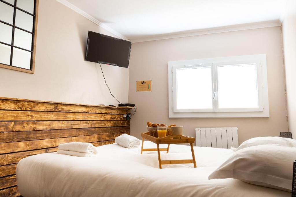 a bedroom with two beds and a tv on the wall at Le Petit Mondi in Mareuil-sur-Cher