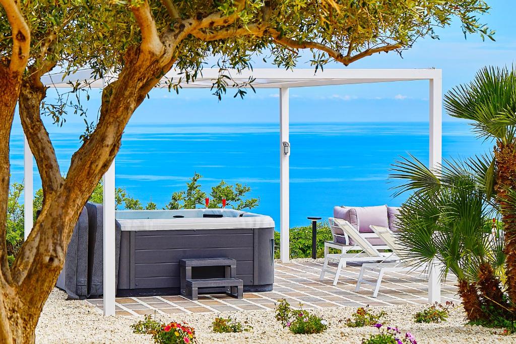 un patio con bañera de hidromasaje y vistas al océano en Villa del Drago, en Scopello