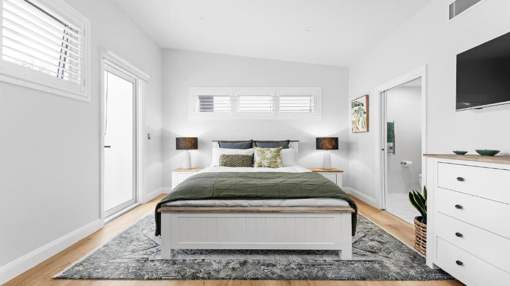 1 dormitorio blanco con 1 cama y TV en Easy Stroll - Ettalong Beach, en Ettalong Beach
