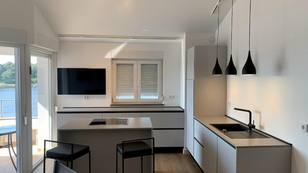 a kitchen with a sink and a counter with chairs at Apartment Nelli in Medulin