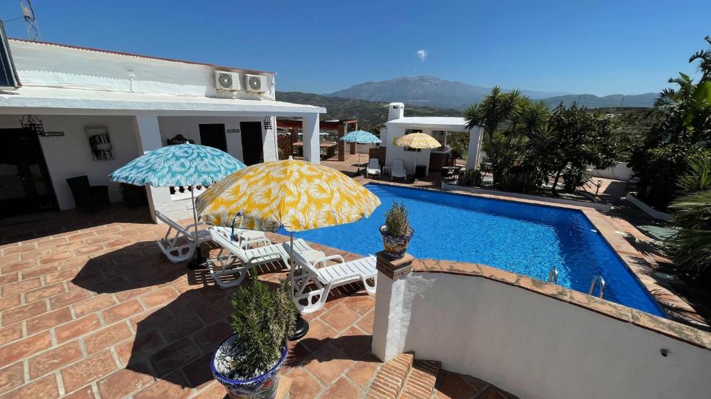 uma piscina com dois guarda-sóis e cadeiras ao lado de uma casa em Casa Bambu-ApartResort em Vélez-Málaga