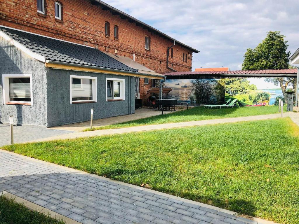 a house with a grassy yard next to a building at Ferienwohnung Seenrunde in Quadenschönfeld