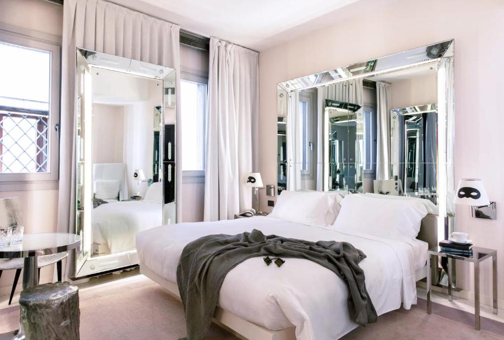 a bedroom with a large white bed and mirrors at Hotel Palazzina Grassi in Venice