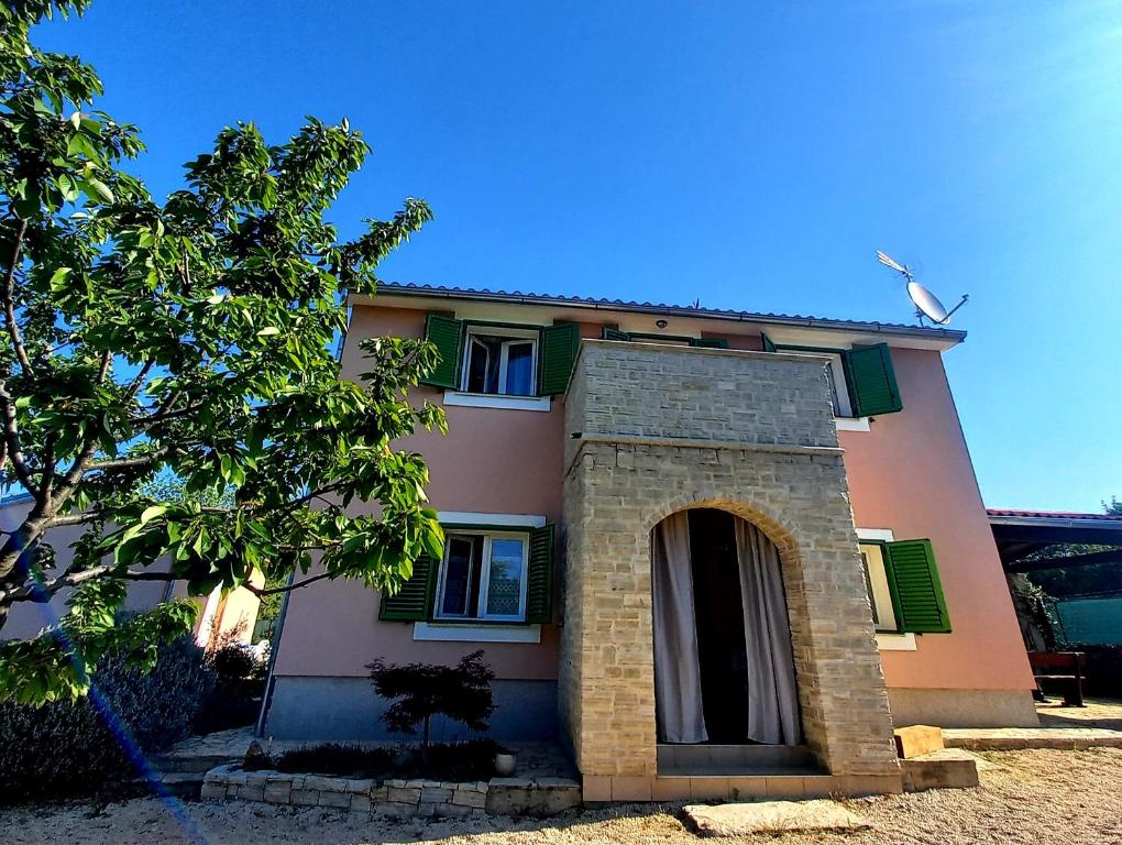 a pink house with a door and a tree at Villa Malini in Grožnjan