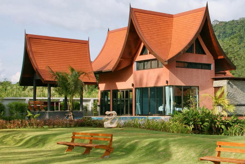 un bâtiment avec un toit orange et un banc devant lui dans l'établissement Tha Lane Bay Villas, à Tha Lane Bay