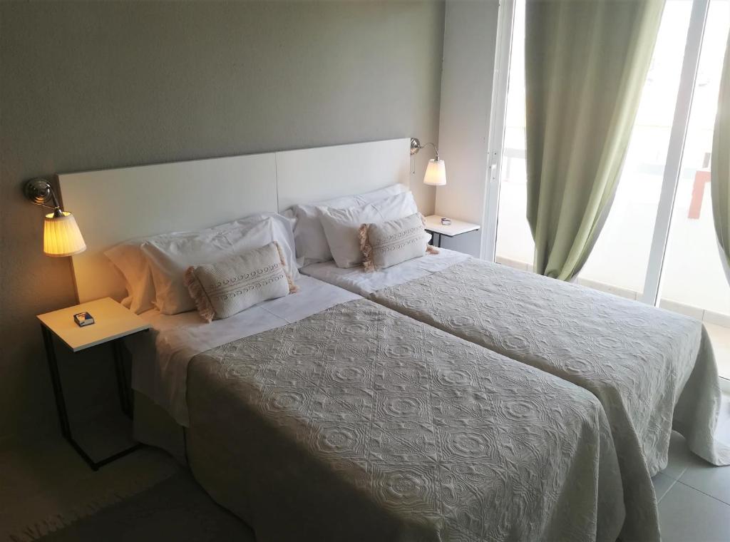 una camera da letto con un letto grande con lenzuola e cuscini bianchi di KC home abroad a Playa de las Americas