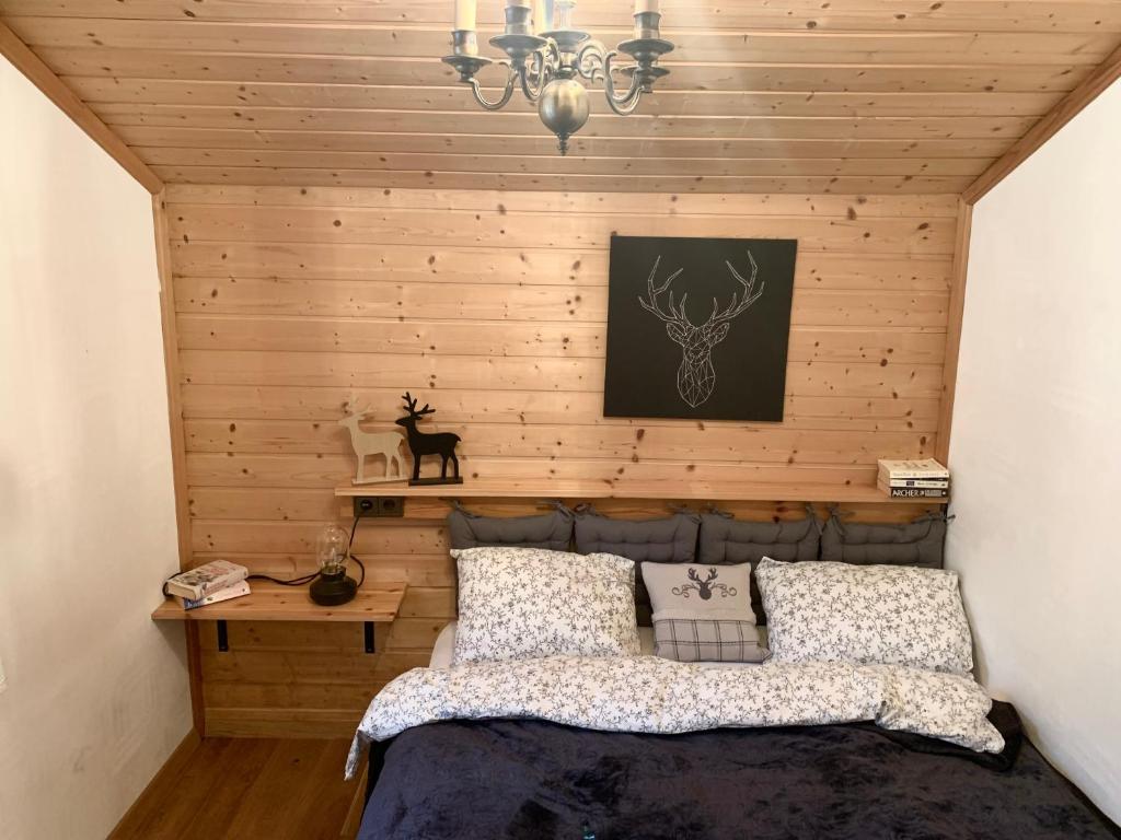 1 dormitorio con 1 cama y pared de madera en Lilly Chalet- Apartments with private sauna, close to ski lifts en Bad Kleinkirchheim