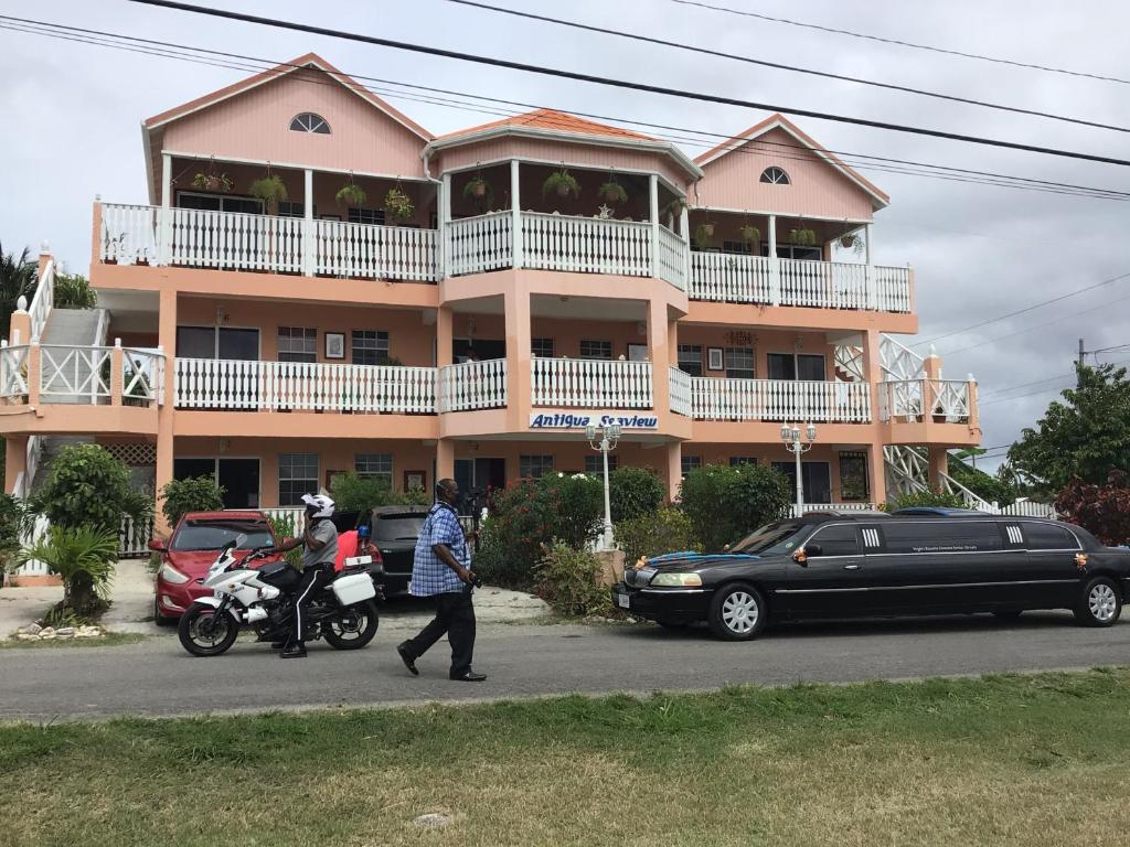 a man riding a motorcycle in front of a building at Antigua Seaview in Saint Johnʼs