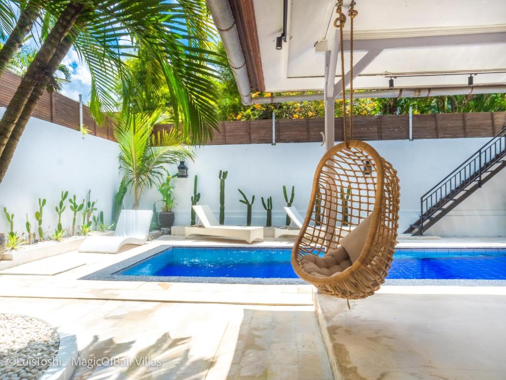 a wicker swing is hanging in front of a swimming pool at The Oberoi Luxury Villas Seminyak in Seminyak