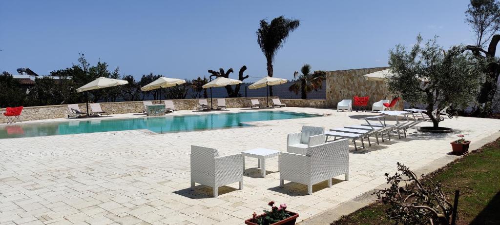 una piscina con sillas y sombrillas blancas en Gli Ulivi Residence, en Leverano